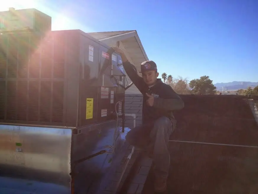 HVAC technician performing Boiler Repair on a rooftop unit in Clanton